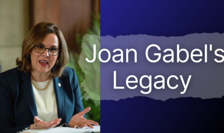 Joan Gabel talking into a microphone at desk, with words saying Joan Gabel's Legacy