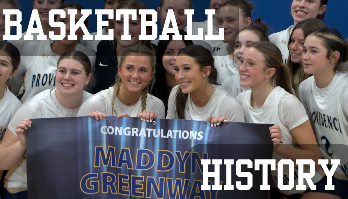 Providence Academy girls’ basketball team poses together after a win over Blake, smiling and holding a banner congratulating Maddyn Greenway on reaching 5,000 career points.