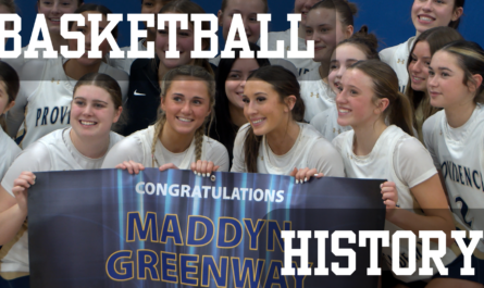Providence Academy girls’ basketball team poses together after a win over Blake, smiling and holding a banner congratulating Maddyn Greenway on reaching 5,000 career points.